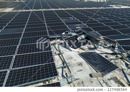 Photovoltaic solar panels destroyed by hurricane strong wind mounted on industrial building roof for producing green ecological electricity. Consequences of natural disaster in Florida 127496564