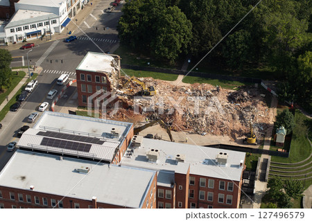 Old building demolition site. Construction excavator tearing down obsolete brick walls. City planning concept 127496579