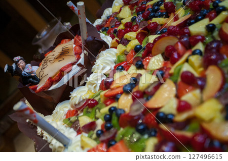 A Colorful and Delicious Fruit Cake adorned with Candles and Beautiful Decorations 127496615