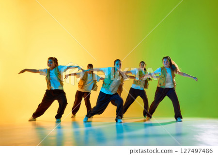 Young dancers embody urban culture with energetic group performance on vibrant colored background 127497486