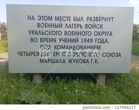 A military camp sign in Russian, detailing the history of the Ural Military District during exercises in 1949 under General Zhukov's command. Surrounded by grass. A military camp sign in Russian, detailing the history of the Ural Military District during exercises in 1949 under General Zhukov's command. Surrounded by grass. 127498217