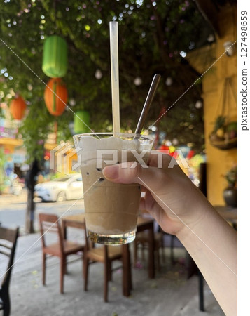 in the girl's hand latte ice coffee put on white background with isolated photo style.latte ice coffee in plastic glass. 127498659