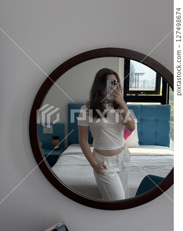 vertical photos Mirror reflection selfie Woman Trying on Outfit Taking a Selfie in a Changing Room Mirror. Funny girl checking her new clothes while posting on social media 127498674