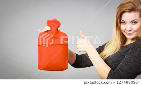 Happy woman holds hot water bottle 127498850