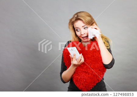 Sad heartbroken woman looking at her phone 127498853