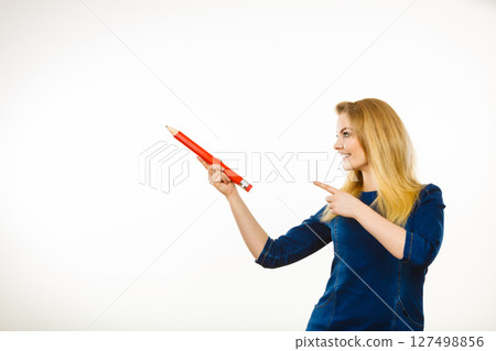 Positive woman holds big pencil in hand 127498856