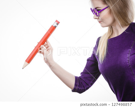 Serious woman holds big pencil in hand 127498857