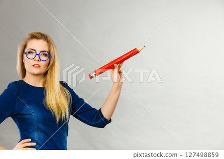 Serious woman holds big pencil in hand 127498859