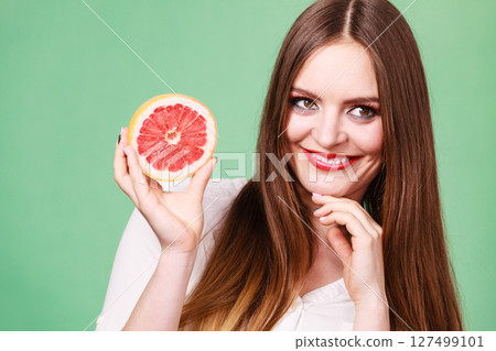 Woman holds half of grapefruit citrus fruit in hand 127499101