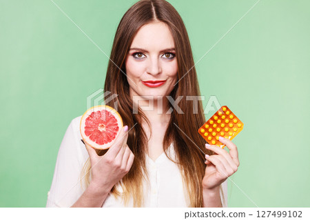 Woman holds grapefruit and pills blister pack vitamin c Woman holds grapefruit and pills blister pack vitamin c 127499102