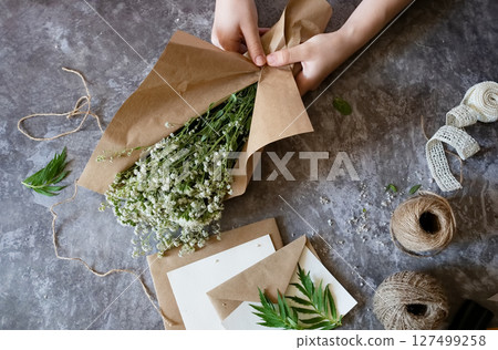 Creating a rustic floral arrangement with natural materials on a textured surface in a cozy crafting space Creating a rustic floral arrangement with natural materials on a textured surface in a cozy crafting space 127499258