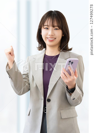 一位年輕女子/女商人拿著智慧型手機擺姿勢 一位年輕女子/女商人拿著智慧型手機擺姿勢 127499278