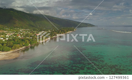 Stunning drone footage captures the idyllic beauty of huahine, French Polynesia, featuring crystal-clear turquoise waters lapping against a lush coastline by vibrant mountains 127499361