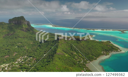 Breathtaking beauty of Bora Bora tropical island, green mountain vegetation, vibrant turquoise lagoon, dramatic volcanic peaks under cloudy sky. Wild travel destination, remote nature paradise. Aerial Breathtaking beauty of Bora Bora tropical island, green mountain vegetation, vibrant turquoise lagoon, dramatic volcanic peaks under cloudy sky. Wild travel destination, remote nature paradise. Aerial 127499362