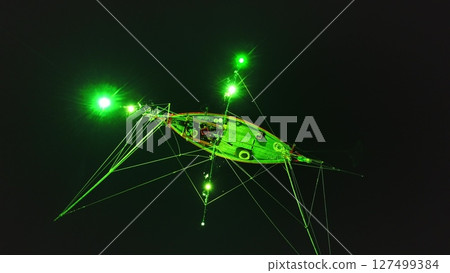 Aerial night view of a traditional Thai squid fishing boat using green lights to attract its prey in the waters surrounding Koh Phangan, Thailand, showcasing a unique fishing technique 127499384