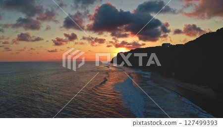 Drone capturing breathtaking sunset over Bali, Indonesia, with vibrant colors illuminating the sky and gentle waves washing onto the shore, creating a serene and picturesque scene Drone capturing breathtaking sunset over Bali, Indonesia, with vibrant colors illuminating the sky and gentle waves washing onto the shore, creating a serene and picturesque scene 127499393