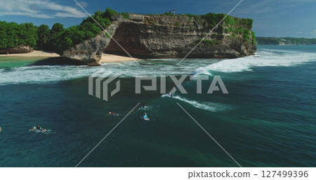 Aerial drone footage of surfers waiting for the perfect wave at the famous Pantai Dreamland Beach, Bali, Indonesia, showcasing the beautiful coastline and lush vegetation Aerial drone footage of surfers waiting for the perfect wave at the famous Pantai Dreamland Beach, Bali, Indonesia, showcasing the beautiful coastline and lush vegetation 127499396