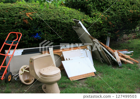 Construction Debris and Discarded Toilet in a Residential Yard 127499503