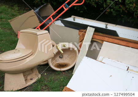Discarded Bathroom Fixtures and Debris Piled on Grass during renovation 127499504