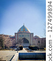 Historic Persian mosque in Erevan Armenia with intricate tilework, golden dome, and archway, surrounded by bare trees under clear blue sky in a peaceful courtyard setting 127499894