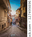 Steep backstreet view with laundry hanging between weathered buildings, capturing daily life and residential texture in a lived-in urban community 127499896