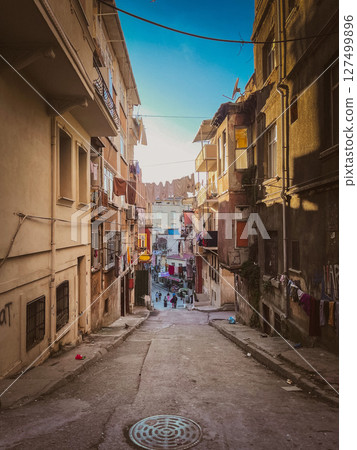 Steep backstreet view with laundry hanging between weathered buildings, capturing daily life and residential texture in a lived-in urban community 127499896