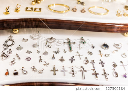 Assortment of gold jewelry in display case. Decorative accessories, luxury items, and retail presentation. Assortment of gold jewelry in display case. Decorative accessories, luxury items, and retail presentation. 127500184