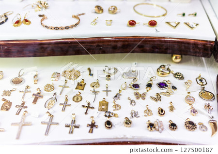 Assortment of gold jewelry in display case. Decorative accessories, luxury items, and retail presentation. 127500187