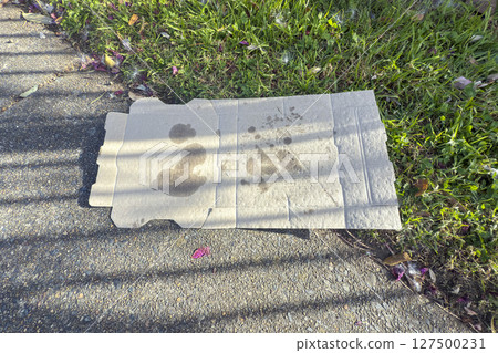 A used and dirty Pizza box left as trash on a footpath A used and dirty Pizza box left as trash on a footpath 127500231