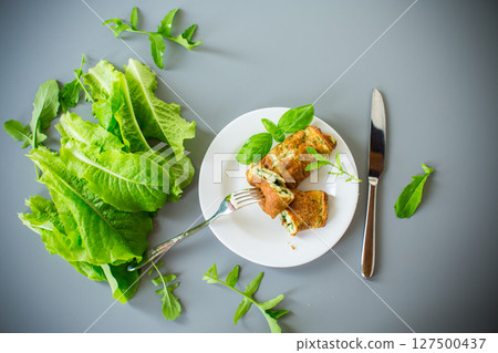 Breakfast of omelette with greens in the form of a roll on top 127500437
