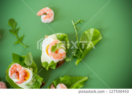Sandwich with egg and shrimp on green background from above 127500450