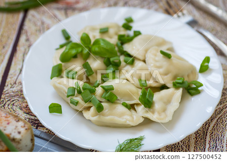 Hot dumplings in a plate with onions on a dark background Hot dumplings in a plate with onions on a dark background 127500452