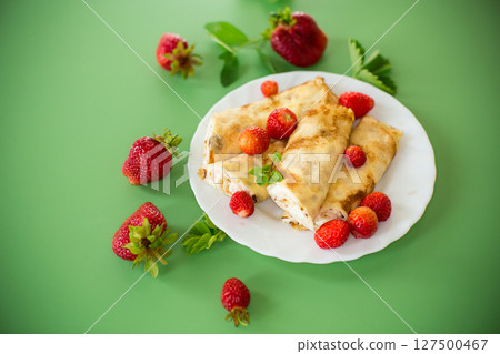 Homemade pancakes with cottage cheese filling and berries on a green background 127500467