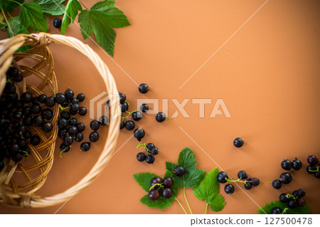 Blackcurrant and berries nearby on brown background 127500478
