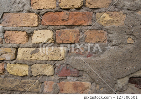 Beige structural stone wall of the ancient building consists of old bricks. 127500501