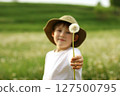 The child holds out a white dandelion. Summer mood, a walk in nature. A gift from the heart 127500795