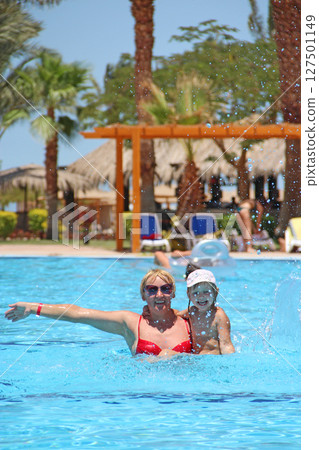 Mother catching her daughter jumping into swimming pool. Happy holidays Mother catching her daughter jumping into swimming pool. Happy holidays 127501149