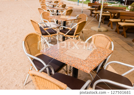 Modern restaurant terrace with set tables and chairs. Casual dining, cozy atmosphere, and summer hospitality experience. 127501681