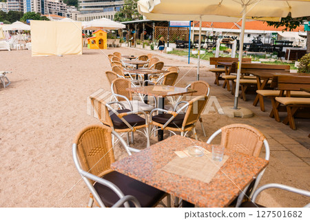 Modern restaurant terrace with set tables and chairs. Casual dining, cozy atmosphere, and summer hospitality experience. Modern restaurant terrace with set tables and chairs. Casual dining, cozy atmosphere, and summer hospitality experience. 127501682