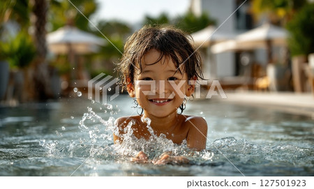 Smiling asian boy in swimming pool splashing water, child playing outdoors on a sunny day 127501923