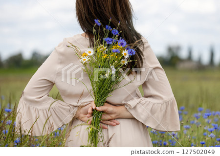 Woman Holding Wildflowers Behind Her Back 127502049