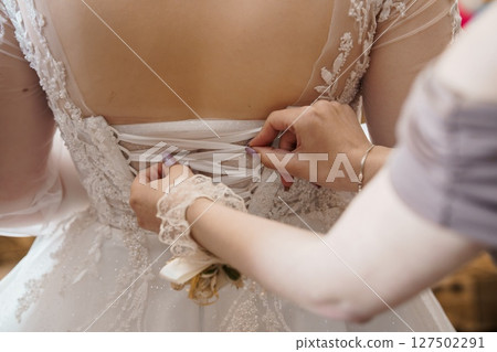 Elegant Bride Getting Ready. Corset Lacing Detail. Wedding Dress Assistance. Ivory Lace. Soft Focus. Bridal Preparation. Intimate Moment. Elegant Bride Getting Ready. Corset Lacing Detail. Wedding Dress Assistance. Ivory Lace. Soft Focus. Bridal Preparation. Intimate Moment. 127502291