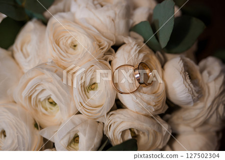 Wedding Rings on White Ranunculus Bouquet: Romantic Ceremony Symbolism with Golden Bands and Soft Floral Details 127502304