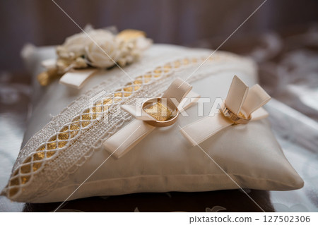 Elegant Wedding Rings on Silk Pillow with Floral Accents: Gold Bands, Cream Lace, Romantic Ceremony Symbolism, Bridal Accessories, Soft Focus Elegant Wedding Rings on Silk Pillow with Floral Accents: Gold Bands, Cream Lace, Romantic Ceremony Symbolism, Bridal Accessories, Soft Focus 127502306