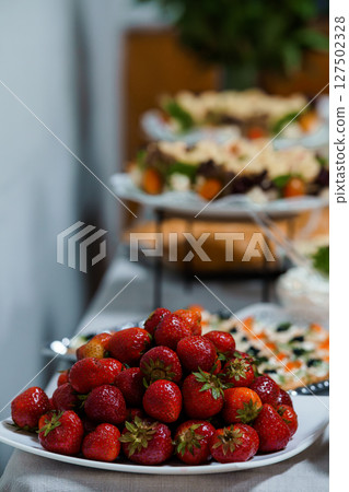 Vibrant Fruit Display at Elegant Event Catering, Fresh Strawberries, Appetizers, Bokeh Background, Festive Party Table, Bright Red and Orange Colors 127502328