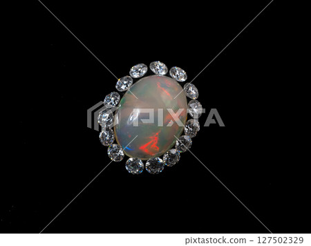Exquisite Oval Opal Ring with Sparkling Diamond Halo. Luxury Fine Jewelry, Black Background, Gemstone Close-up, Colorful Fire, Elegant Design Exquisite Oval Opal Ring with Sparkling Diamond Halo. Luxury Fine Jewelry, Black Background, Gemstone Close-up, Colorful Fire, Elegant Design 127502329