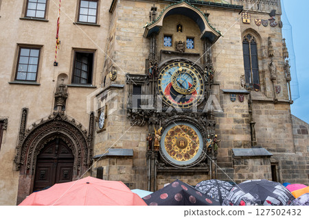 Prague, Czech Republic, August 5, 2023. The astronomical clock is one of the main attractions of the old town. On a rainy day, people with umbrellas crowded to see it. Travel destinations. Prague, Czech Republic, August 5, 2023. The astronomical clock is one of the main attractions of the old town. On a rainy day, people with umbrellas crowded to see it. Travel destinations. 127502432