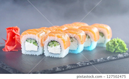 Bioluminescent sushi rolls glowing on dark stone platter with wasabi forest. Generated Image 127502475