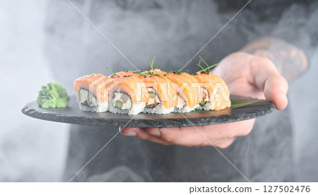 Bioluminescent sushi rolls glowing on dark stone platter with wasabi forest. Generated Image 127502476
