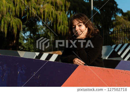 Smiling woman peeking out from a colorful wall 127502718